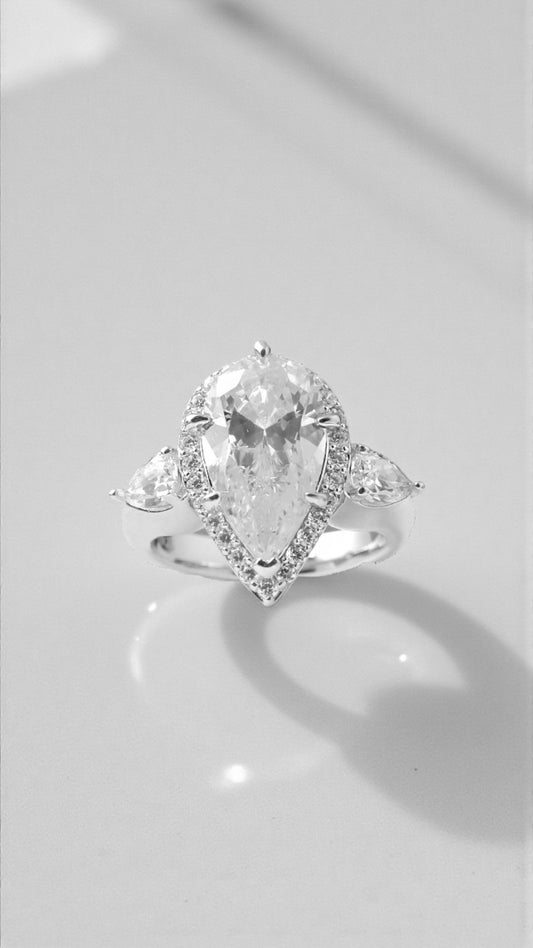 Anillo centro talla pera con orla alrededor